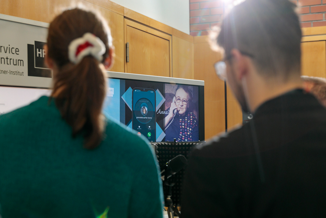 The exhibit shows the phone application of a smartphone. A call from a grandchild is shown. Next to it is an old person holding a telephone receiver. The question "Anna?" is written above the picture.