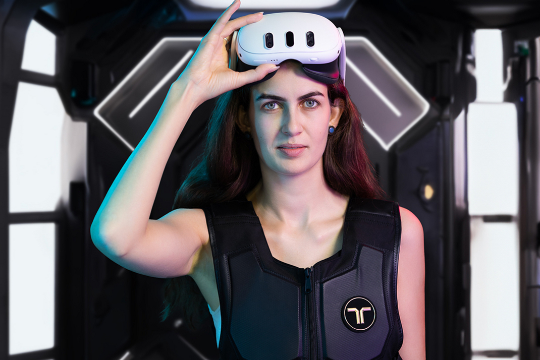 A person presents VR equipment consisting of glasses and a vest.