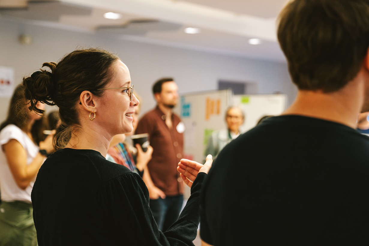 Teilnehmende tauschen sich in einer Workshop-Situation in kleinen Gruppen aus.
