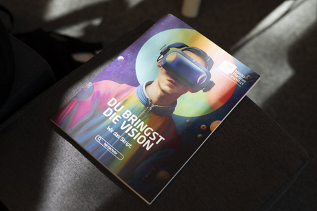 The photo of a magazine. The cover shows a person wearing VR glasses. It says "You bring the vision - we bring the script."