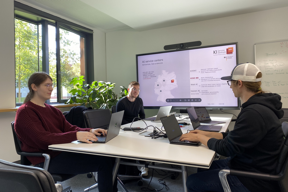 Two AI experts in a meeting with pilot project participants, all seated at a table with laptops.