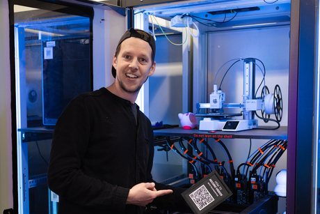 Markus Wutzlhofer presents the 3D printer at HPI Maker Universe, giving a friendly smile to the camera.
