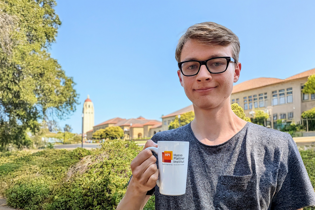 HPI bachelor's student Valentin Teutschbein on the Stanford University campus with a HPI mug in his hand.