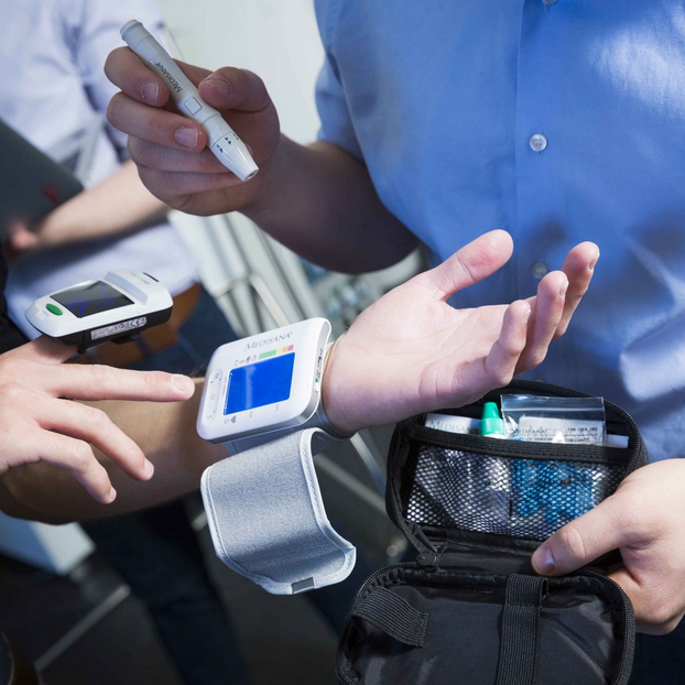 An image of hands. A medical wearable around a wrist.