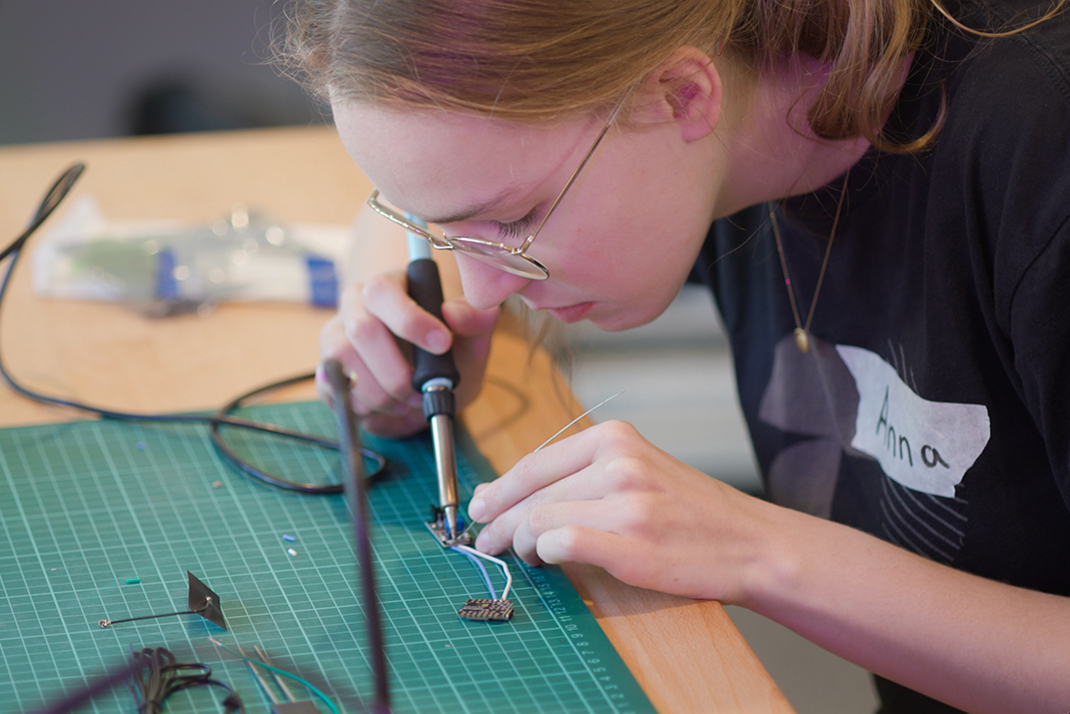 A participant in HPI Maker Universe soldering small cables to a circuit board 