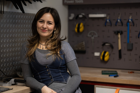 A portrait photo of Kat Posegga. Behind her is a tool rack.