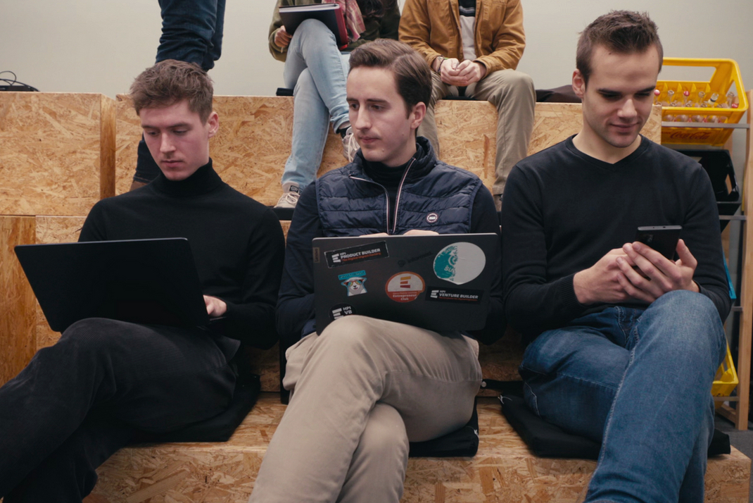 Niklas Kämmer sitzt mit anderen Studenten auf einer Bank. Er arbeitet mit einem Laptop auf seinem Schoß.