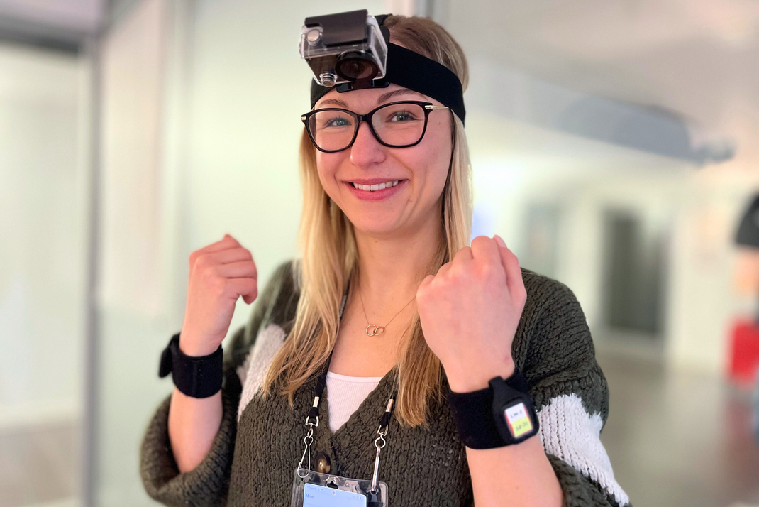 Ph.D.-Kandidatin am HPI Kristina Kirsten präsentiert das System aus Stirnband-Kamera und Bewegungssensoren an den Handgelenken.