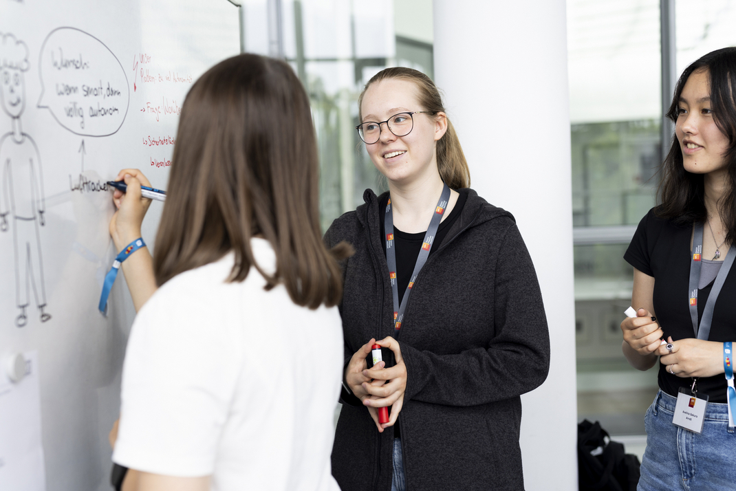 Teilnehmerinnen schreibt Ergebnisse an ein Whiteboard 