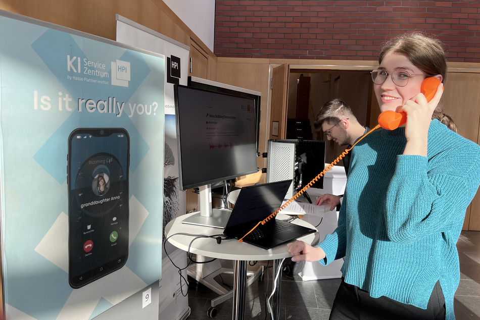 Woman holding a telephone handset, in the background a roll-up reading “Is it really you?”