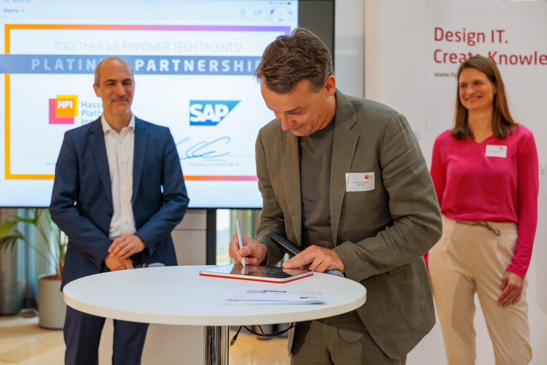 SAP-Vorstandsvorsitzender Christian Klein unterschreibt die Kooperationsvereinbarung mit dem HPI. Hinter ihm stehen HPI-Geschäftsführer Prof. Tobias Friedrich (links) und Dr.-Ing. Katharina Schäfer, Global Head of University Alliances bei SAP