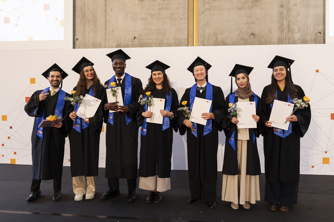 The group photo shows graduates proudly displaying their diplomas
