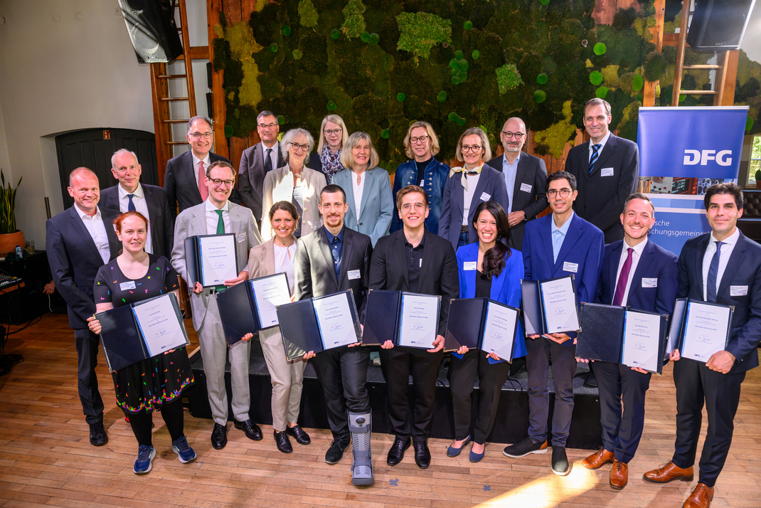Group photo of the award winners and members of the DFG. The award recipients are presenting their certificates.