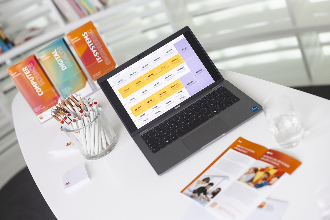 Table with informational materials, writing utensils, and an open laptop displaying a sample study plan