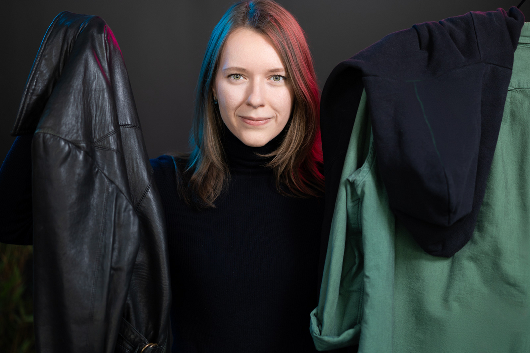 HPI doctoral student Aleksandra Kudaeva looks straight into the camera, holding a jacket in each hand.