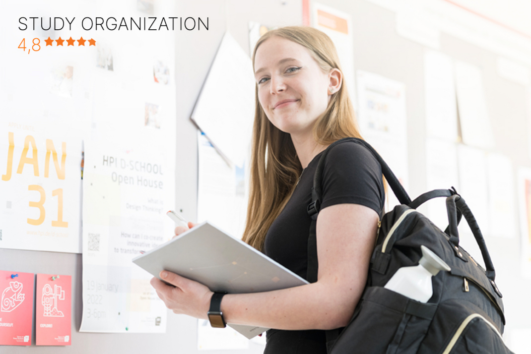 A student at the Hasso Plattner Institute stands in front of a notice board in the institute building and looks friendly into the camera. She is carrying a backpack over her shoulder and holding a writing pad in her hands. In the upper right corner of the picture is a purple seal of the current CHE Master's ranking. At the bottom of the picture is a bar with the HPI's rating in the category “Study Organization” (4.8 out of 5 stars).